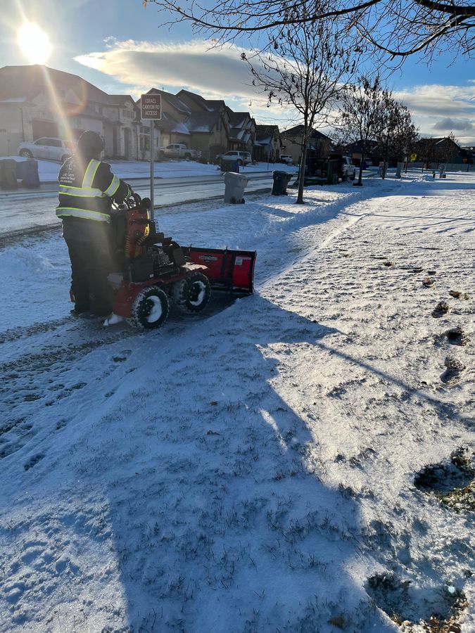 Stand-on plow clearing a sidewalk